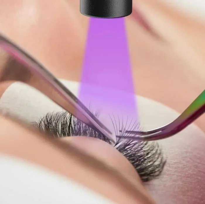 Close-up of UV lash extensions being cured with a violet light